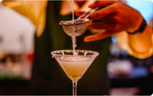 Barman en train de filtrer un liquide se déversant dans un verre à cocktail